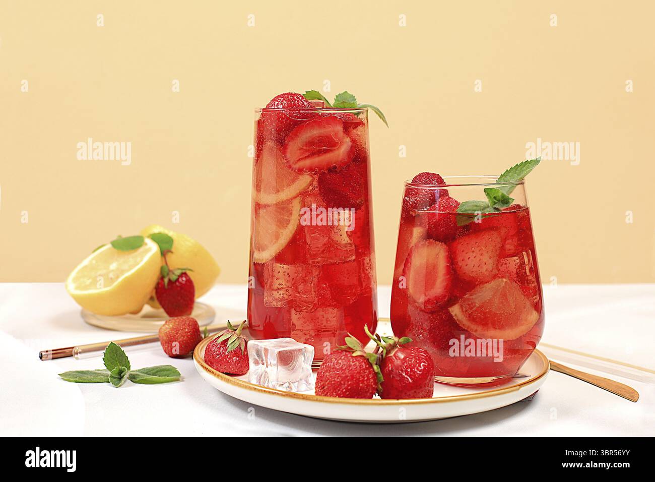 Erdbeere Iced Tea oder Minze Lemon Cocktail ist ein erfrischendes Sommergetränk. Gläser mit Beerenfrucht-Limonade auf einem hellen Betontisch, Detox-Würfel Stockfoto