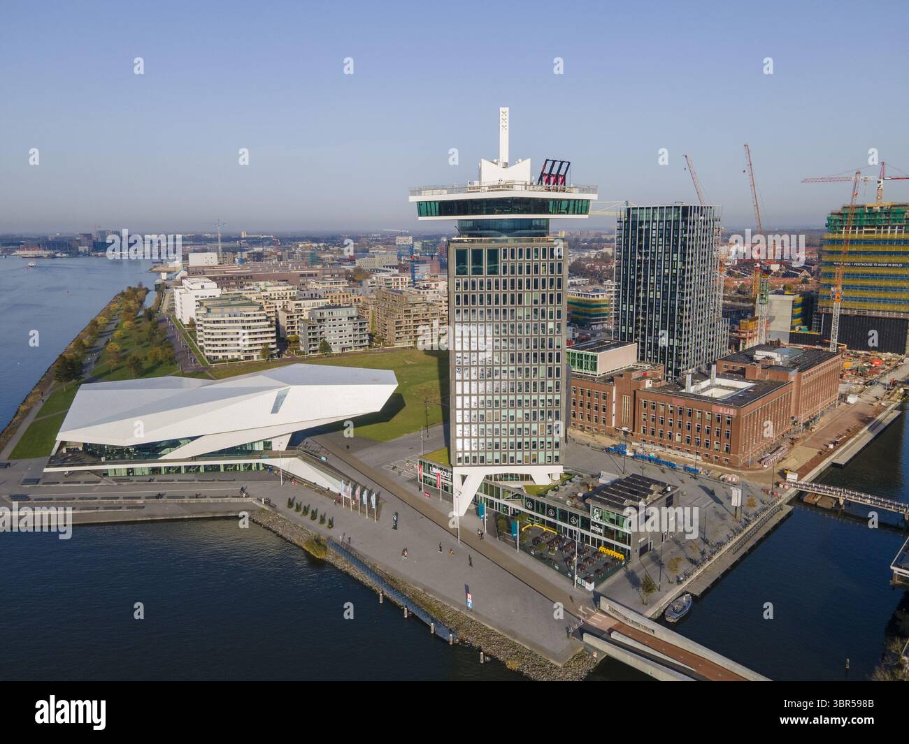 Aus der Vogelperspektive die Aussichtsplattform A'DAM Lookout und das EYE Film Institute im Kontrast zur Skyline der Stadt und den Wasserstraßen, Amsterdam, Nordholland, Niederlande. Stockfoto