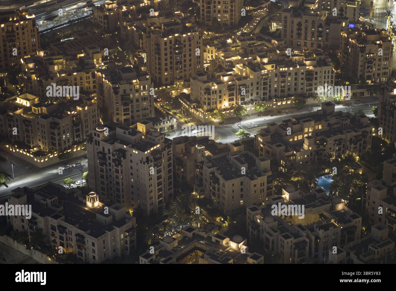 Dubai, Vereinigte Arabische Emirate - 16. Juni 2025: Aus der Vogelperspektive auf das goldene Leuchten einer Stadt, wo warme Lichter die komplizierten Muster von Gebäuden und Straßen darunter beleuchten. Stockfoto
