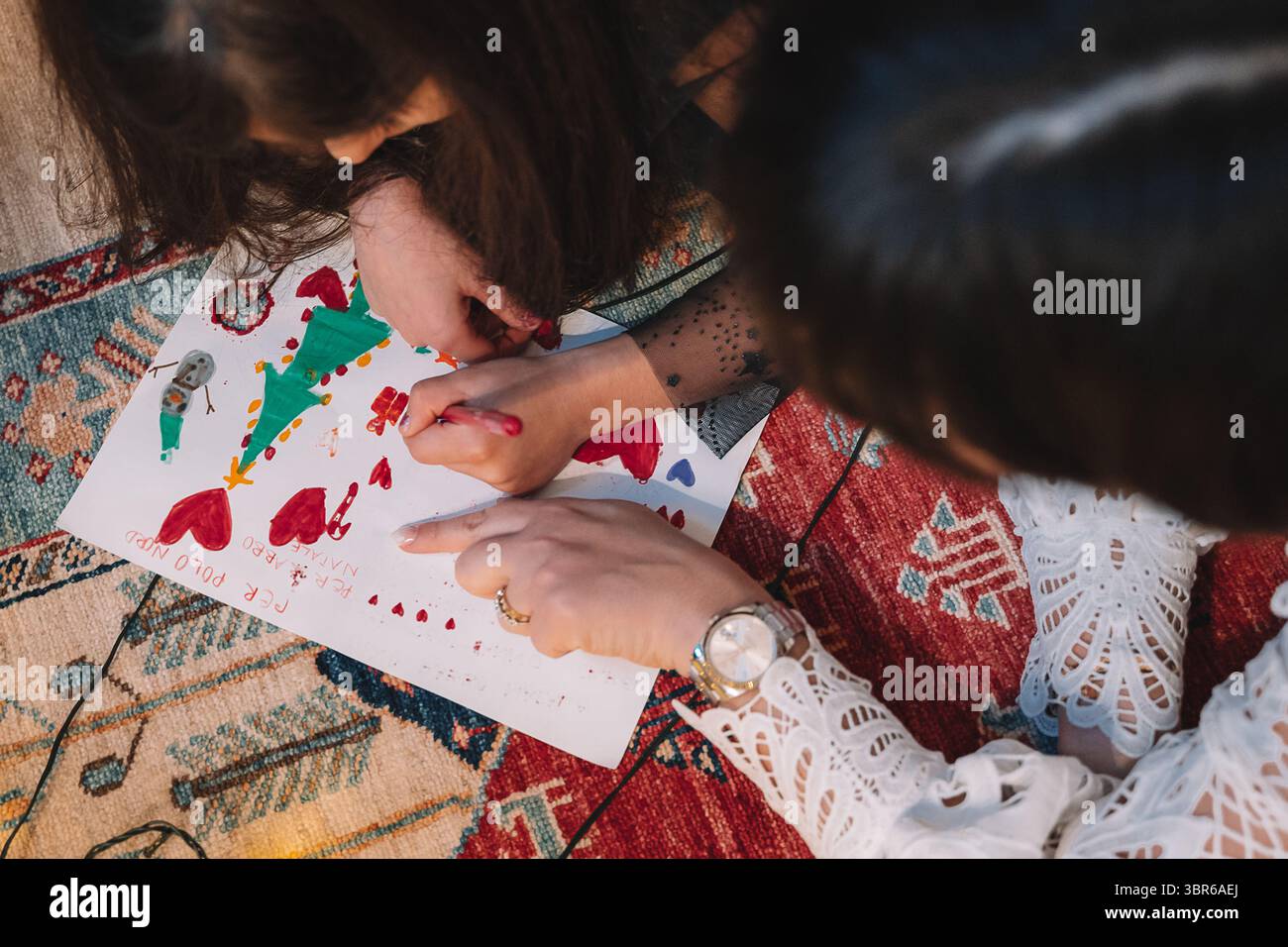 Die Kinder haben eine kreative Zeichenaktion durchgeführt und ein farbenfrohes Weihnachtsmotiv auf Papier mit Markierungen gebastelt. Die Aktivität wird auf einem Muster festgelegt Stockfoto