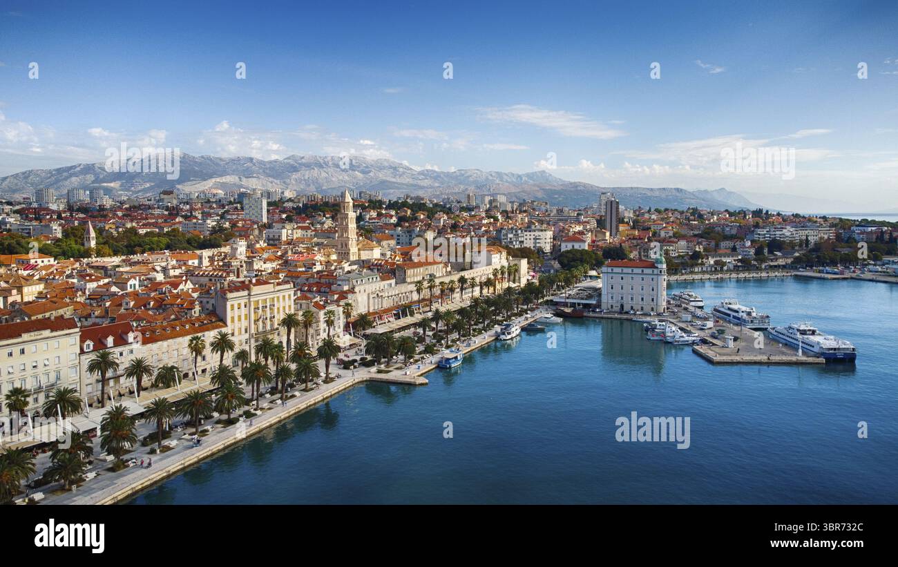 Blick aus der Vogelperspektive auf die Terrakotta-Dächer, die sich in Richtung des hackernen Hafens stürzen, eingerahmt von fernen, schneebedeckten Bergen und dem berühmten Glockenturm von St. Domnius, Split, Kreis Split-Dalmatien, Kroatien. Stockfoto