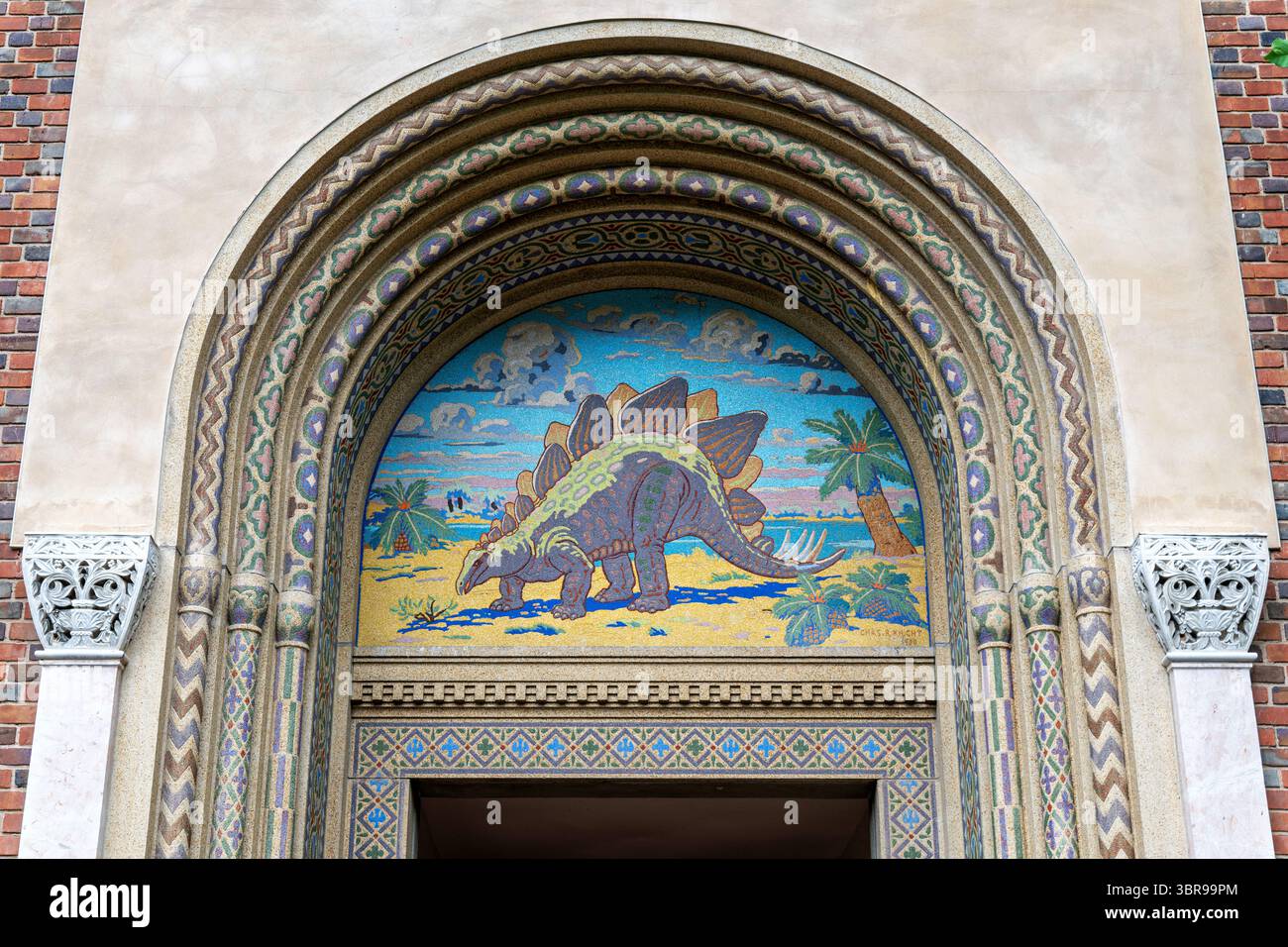 WASHINGTON DC – Ein Stegosaurus-Mosaik ziert den Haupteingang des Reptile Discovery Center des National Zoo, das 1931 in Zusammenarbeit mit dem Architekten Albert L. Harris, dem Paläokünstler Charles R. Knight und dem Betonpionier John Joseph Earley entstand. Das Mosaik wurde mit Earleys revolutionärer Betontechnik ausgeführt, bei der farbige Zuschlagstoffe direkt in weißen Portland-Zement gemischt wurden, um lichtbeständige Farben zu erzeugen, die in das Material integriert sind. Knight, Amerikas bedeutendster Paläokünstler, der in großen Naturkundemuseen arbeitete, entwarf den wissenschaftlich präzisen Stegosaurus auf der Basis von exten Stockfoto