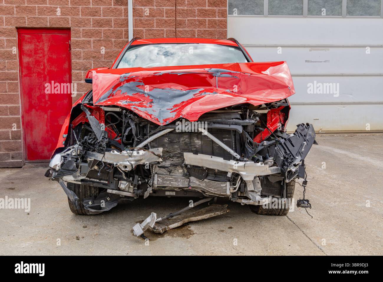 Rotes Fahrzeug mit schweren Schäden an der Front aufgrund eines Autounfalls. Stockfoto