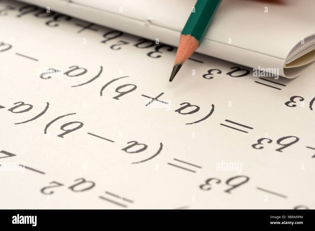 Der Bleistift liegt auf einem Notizbuch mit Gleichungen und mathematischen Symbolen auf. Stockfoto