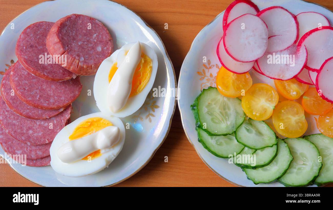 Köstliches Frühstück mit Aufschnitt, gekochten Eiern und lebendigem Gemüse. Stockfoto