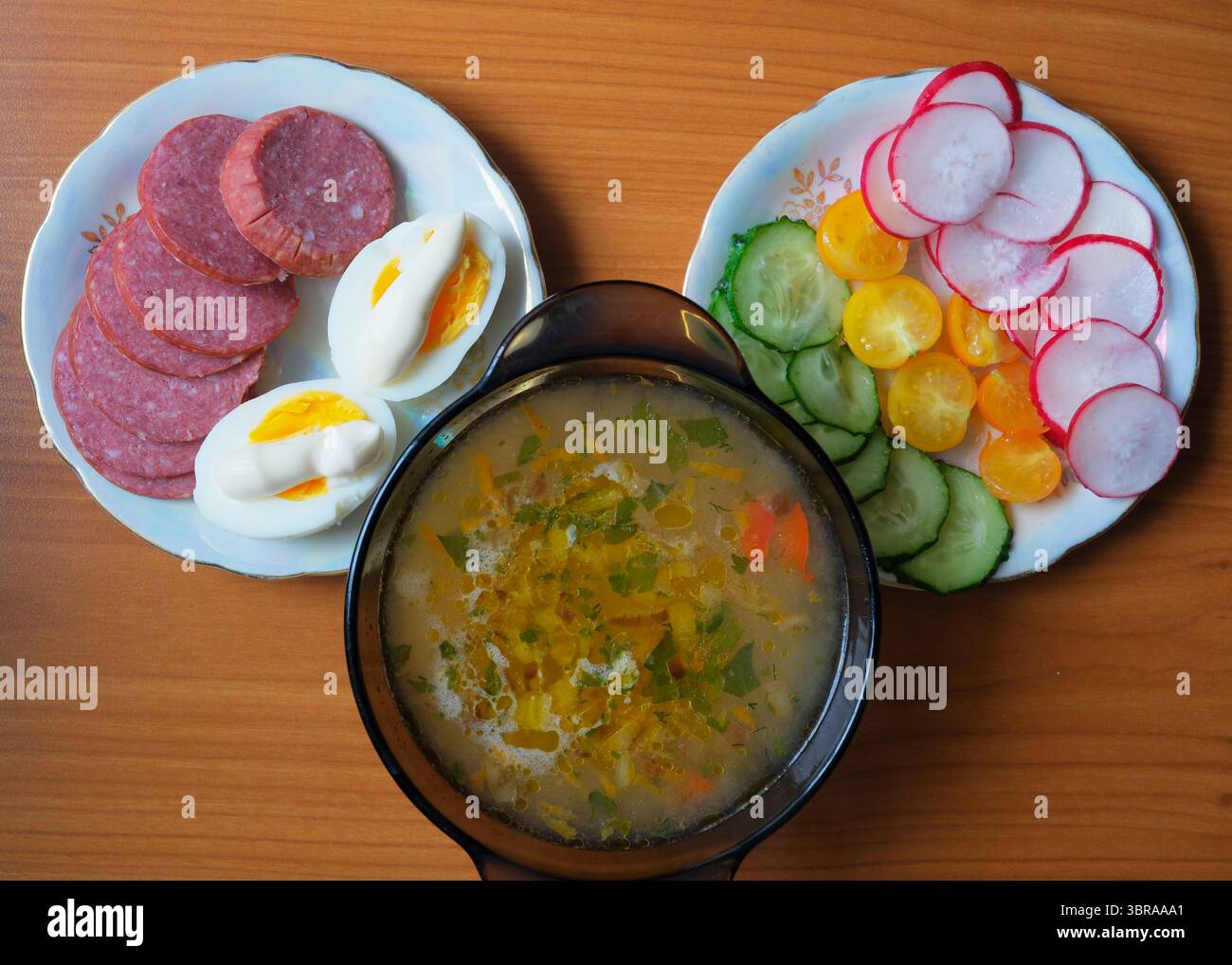Eine lebhafte Mahlzeit auf Tellern mit Suppe und frischem Gemüse mit Eiern. Stockfoto