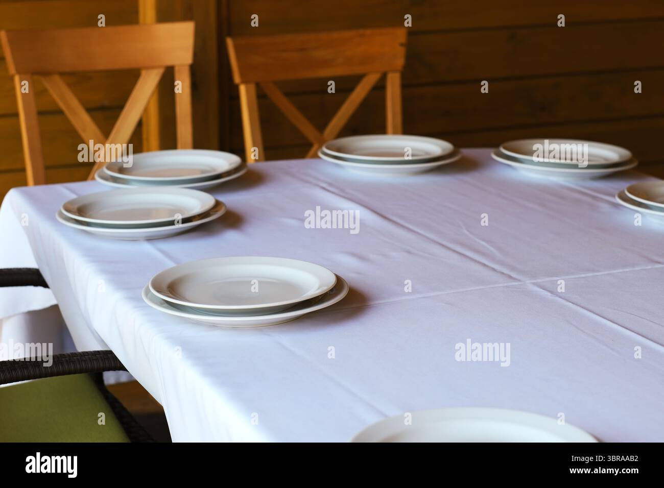 Elegantes Tischset mit weißen Tellern, bereit für ein warmes Treffen mit Lieben. Stockfoto