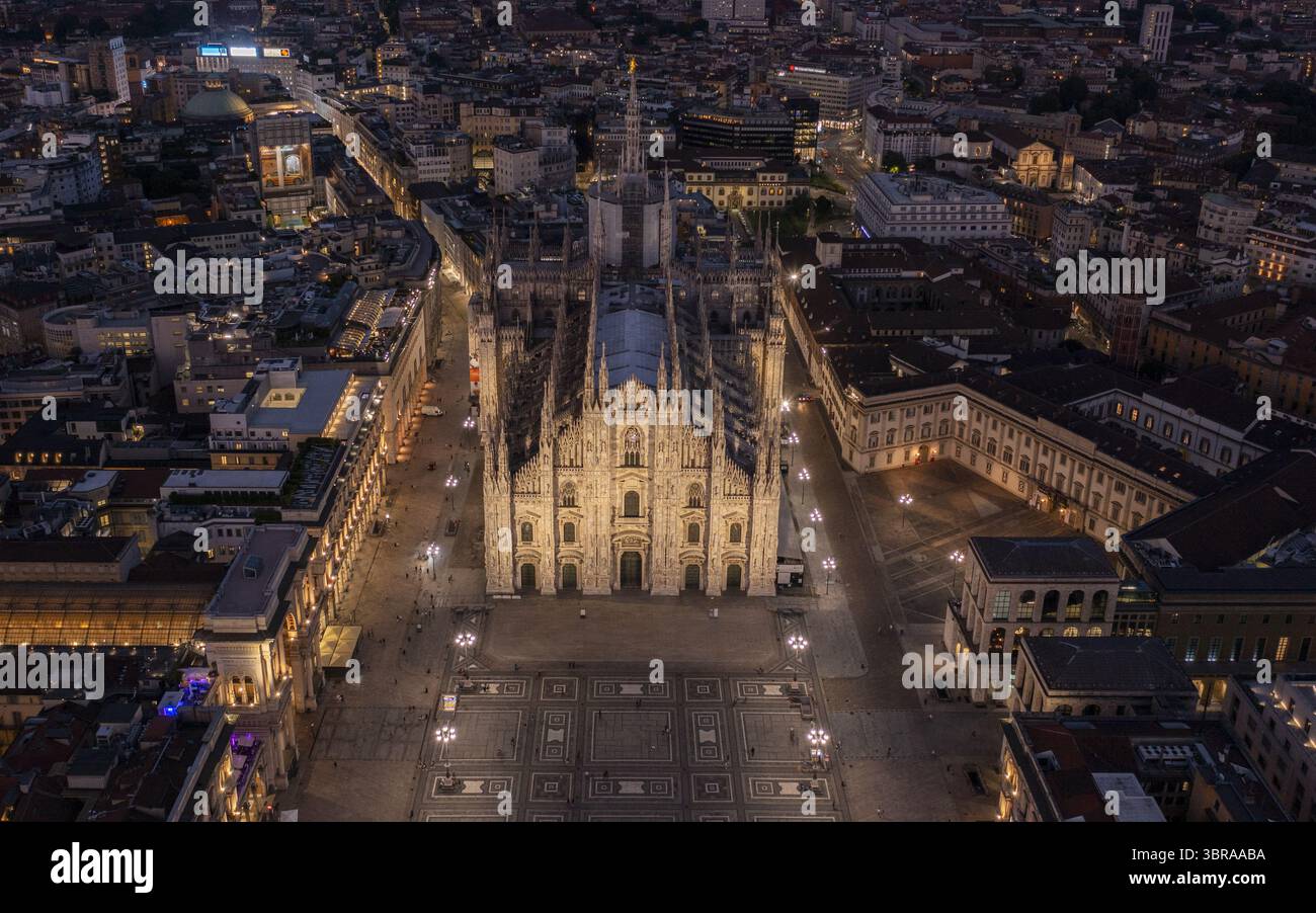 Aus der Vogelperspektive des beleuchteten Duomo di Milano, der ein warmes Leuchten auf die gemusterte piazza unter sich wirft, im Kontrast zu den kühlen Lichtern der Stadt, Mailand, Lombardei, Italien. Stockfoto