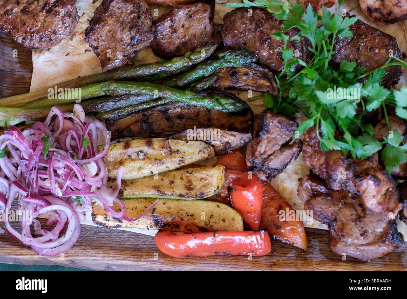 Genießen Sie eine leckere Mischung aus gegrilltem Fleisch und frischem Gemüse, die auf Ihre Gäste warten! Stockfoto