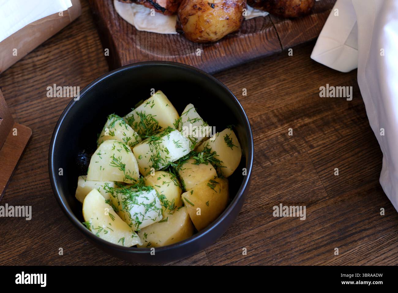 Eine warme Schüssel mit zarten Kartoffeln, garniert mit duftenden grünen Kräutern wartet auf den Genuss. Stockfoto