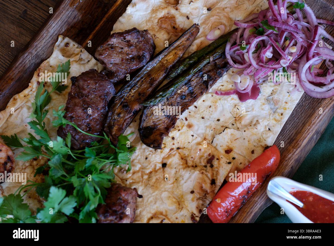 Saftiges gegrilltes Fleisch und Gemüse werden kunstvoll auf Fladenbrot mit Kräutern zubereitet. Stockfoto