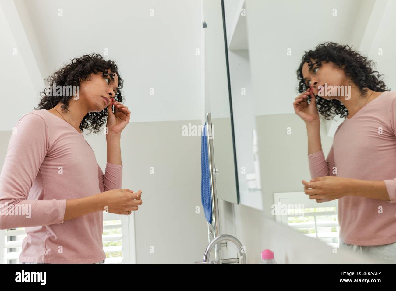 Afroamerikaner, nicht binäre Person, die Eyeliner am Waschbecken im Badezimmer mit Spiegel, Kopierraum aufträgt Stockfoto