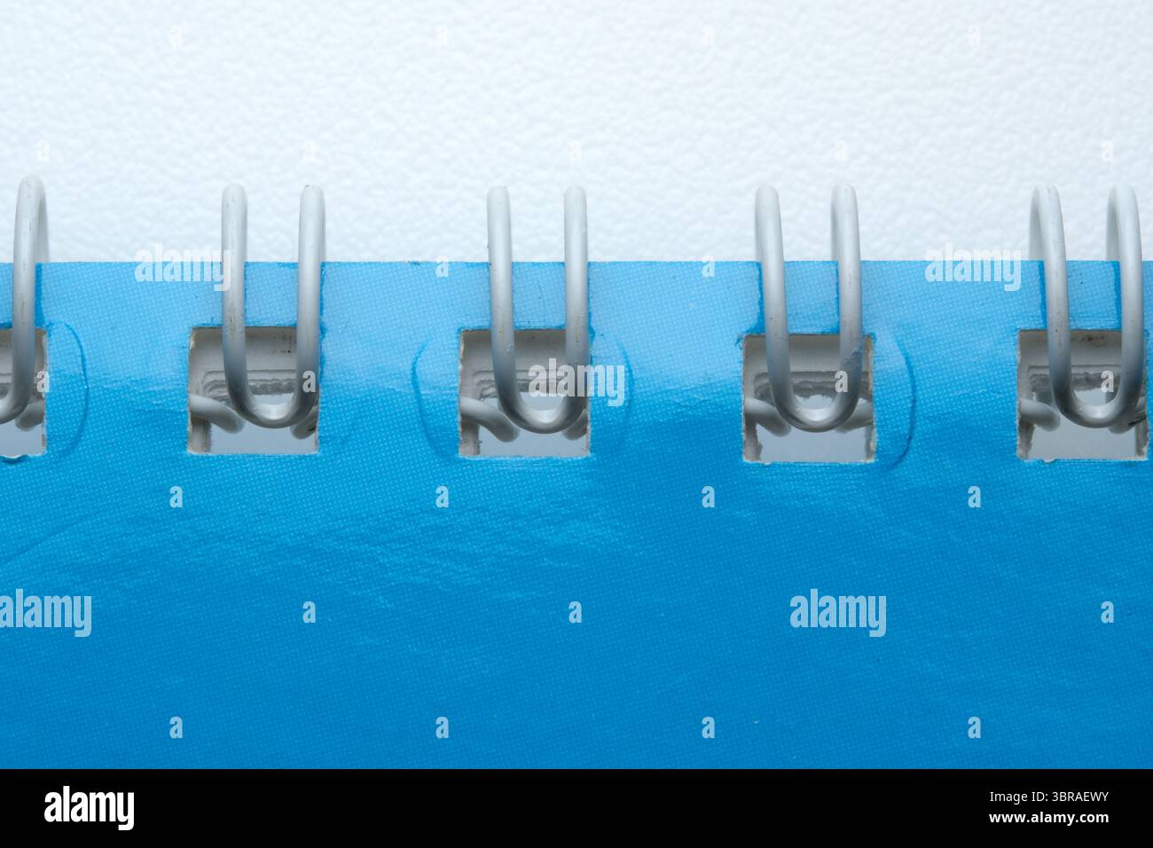 Farbenfrohe Spiralbindung auf einem lebhaften blauen Notizbuch unterstreicht die Kunst im Detail. Stockfoto
