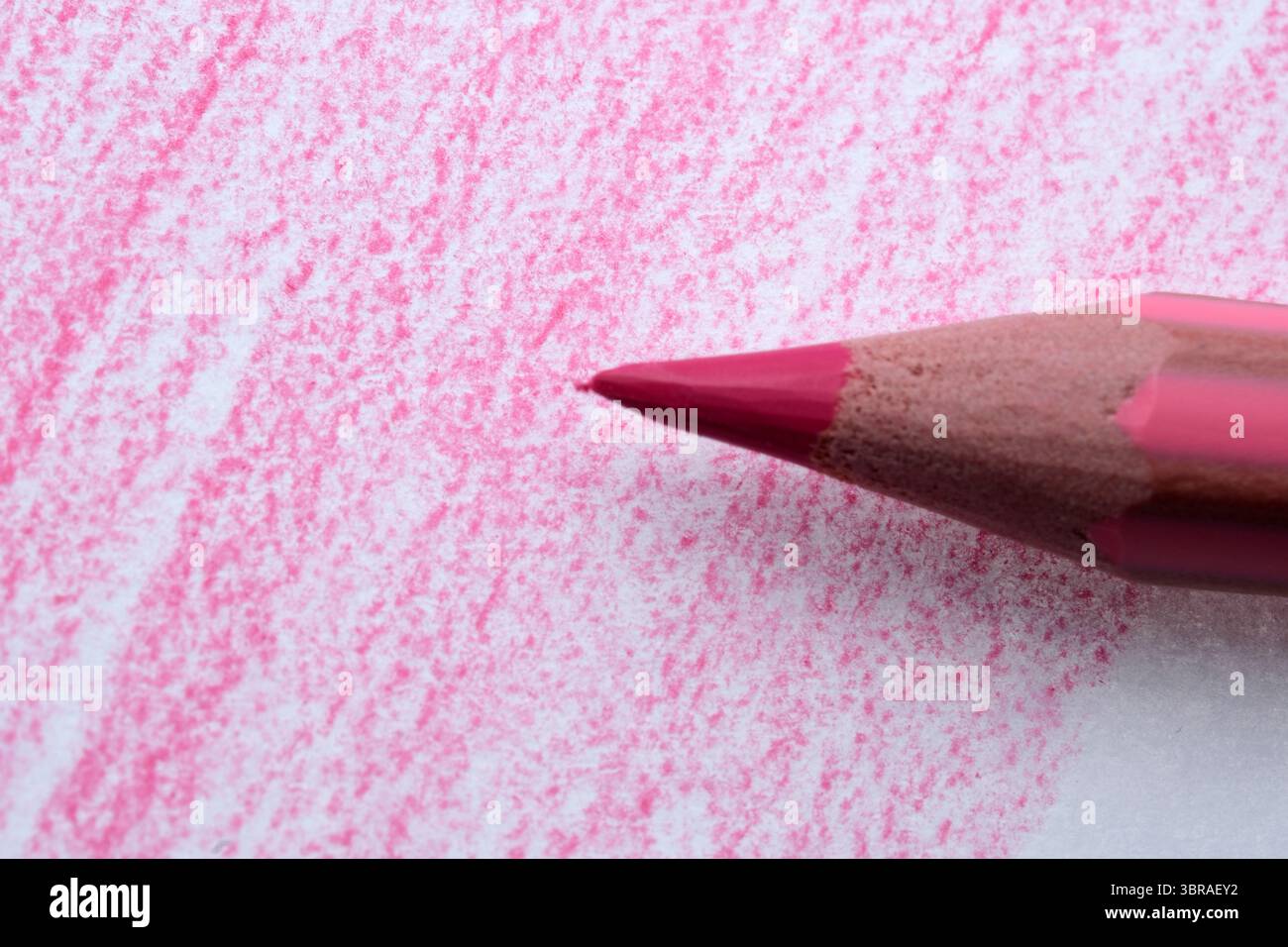 Eine Nahansicht eines rosafarbenen Bleistifts, der bunte Muster auf Papier zeichnet. Stockfoto