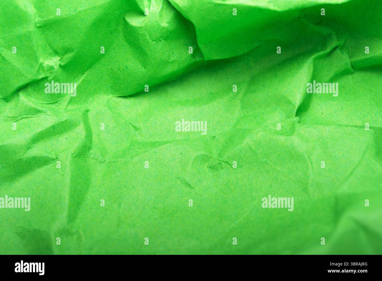 Zerknittertes grünes Papier erzeugt ein visuell ansprechendes abstraktes Muster. Stockfoto
