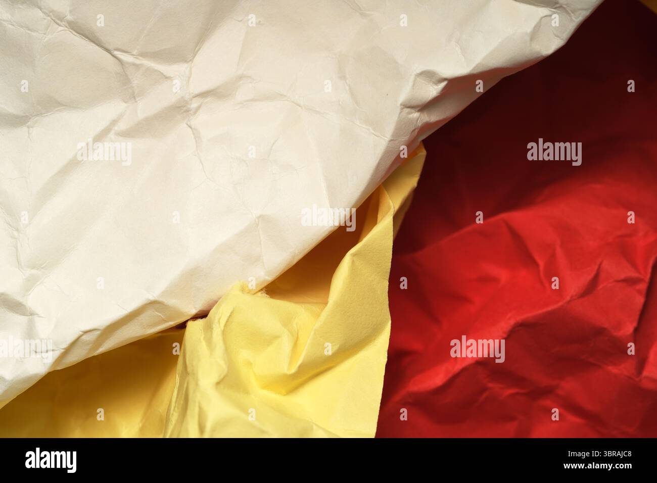 Strukturierte Schichten aus lebendigem Papier zeigen Schatten und Falten. Stockfoto