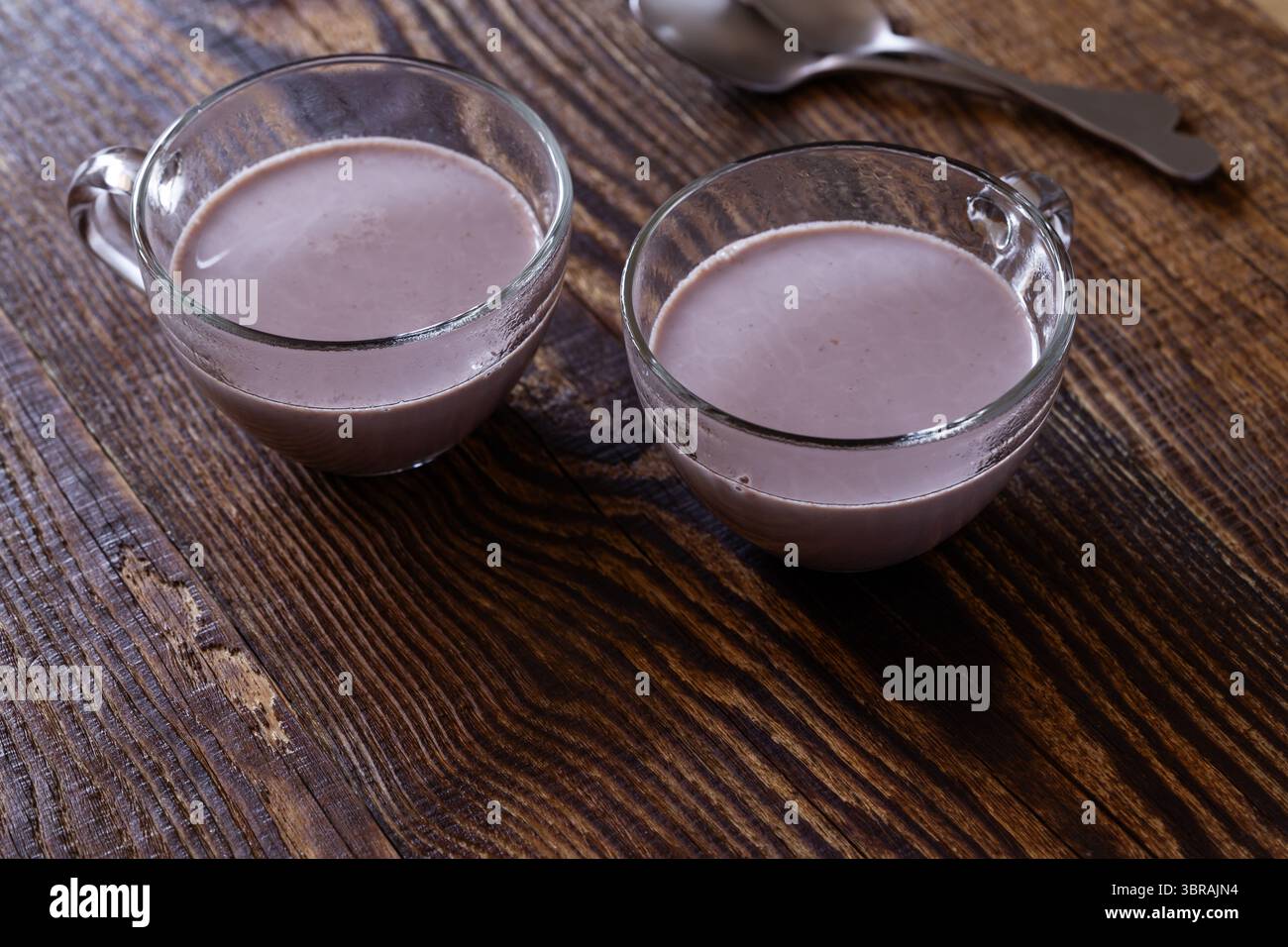 Süße heiße Schokolade in Glasbecher auf hölzernem Hintergrund Stockfoto