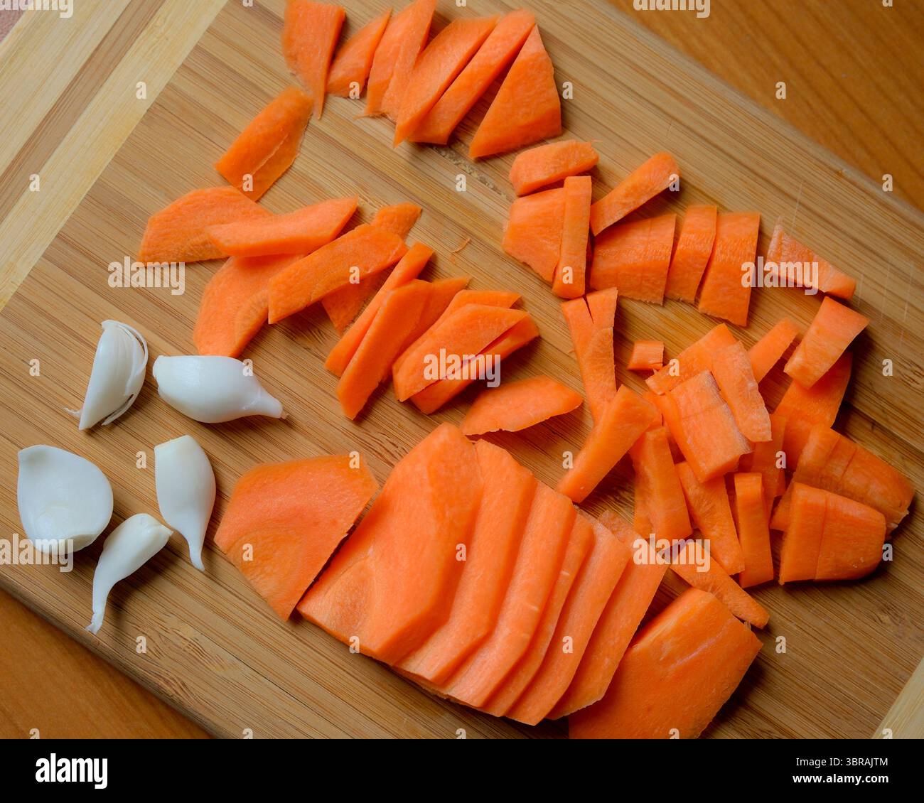Frisch gehackte Karotten liegen auf einem Holzbrett, fertig zum Kochen. Stockfoto