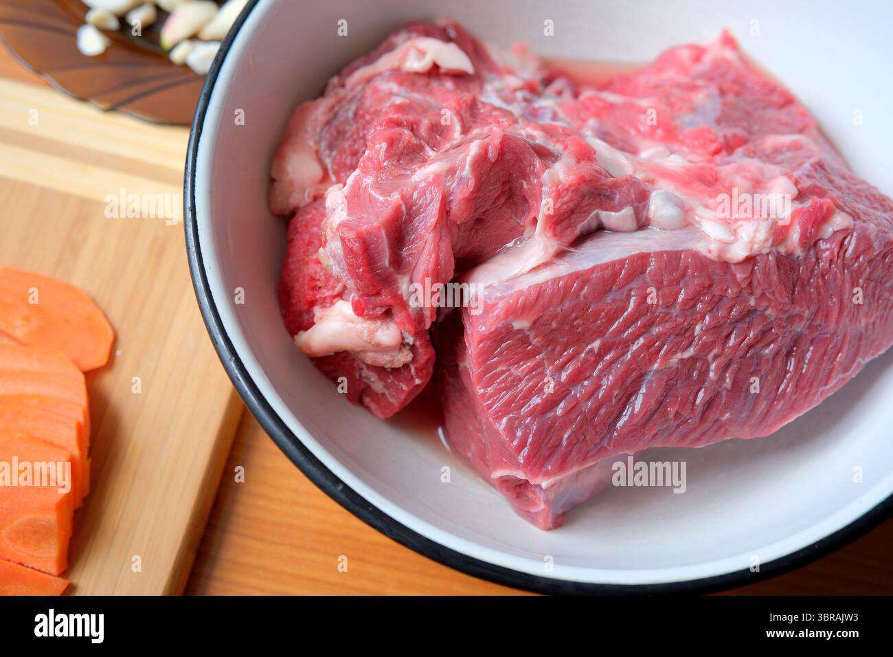 Rohes Fleisch wird in eine Schüssel gegeben und wartet darauf, in ein herzhaftes Gericht verwandelt zu werden. Stockfoto