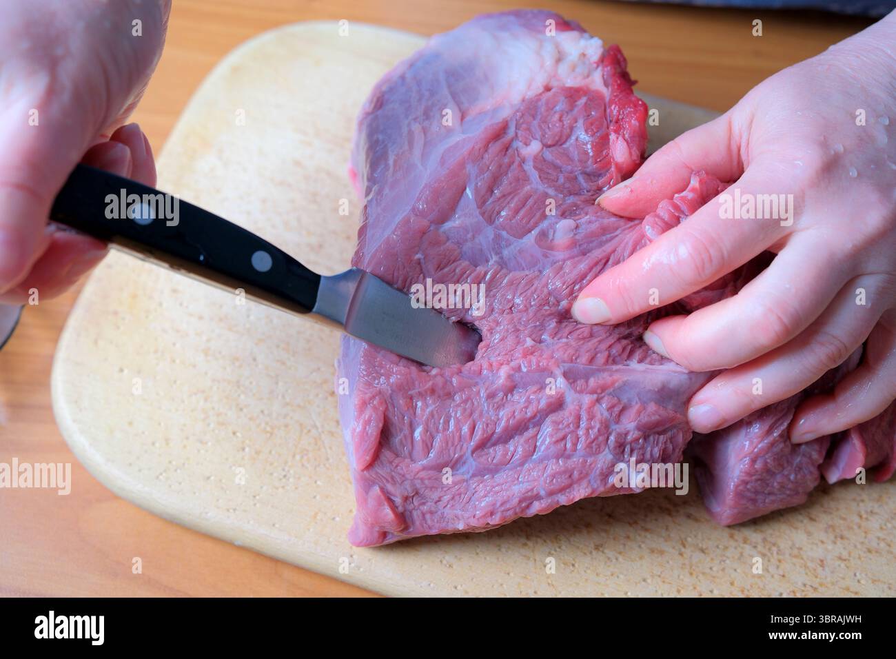 Das präzise Schneiden eines frischen Fleischstücks unterstreicht die kulinarischen Fähigkeiten beim Spielen. Stockfoto