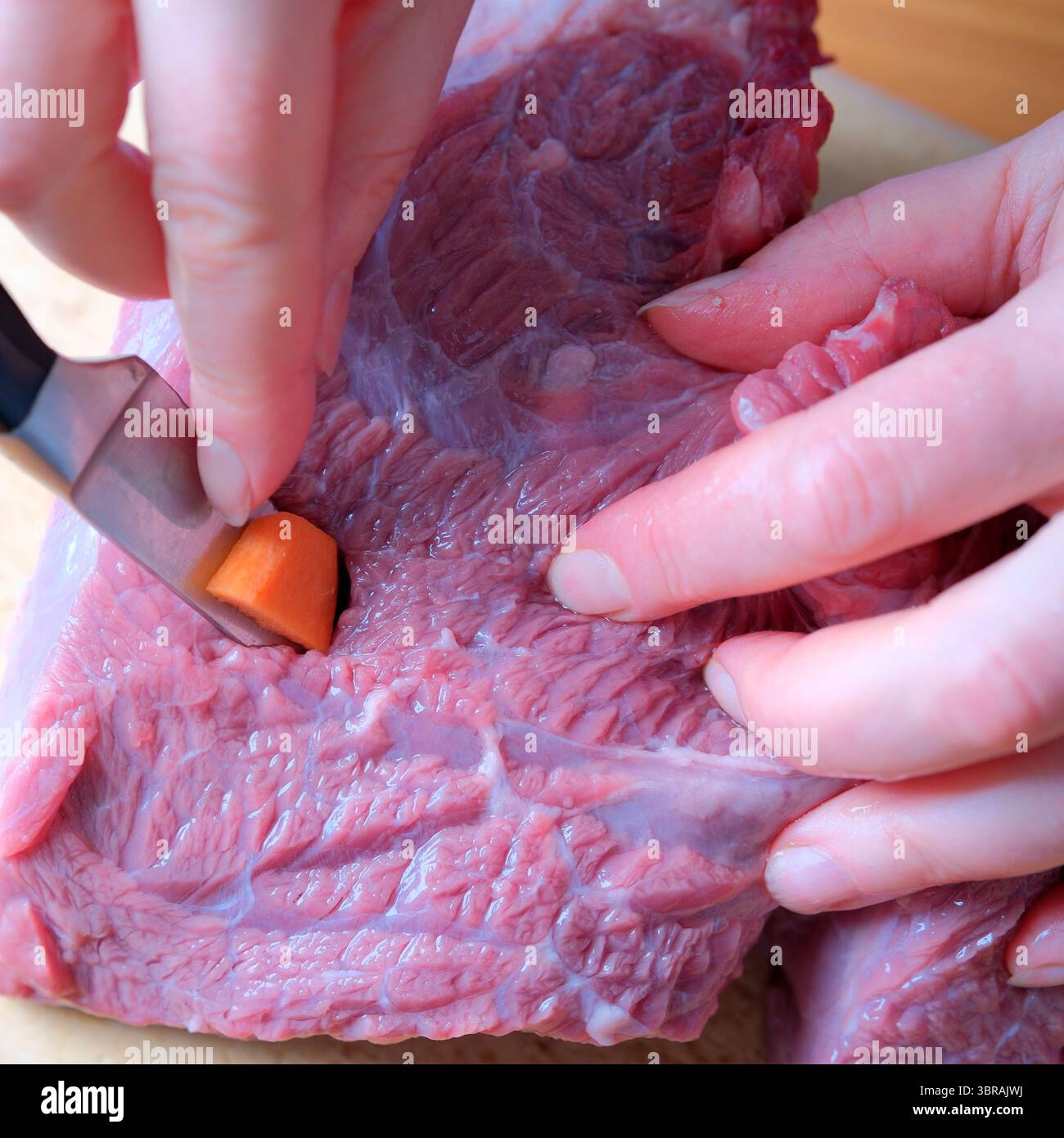 Fachkundige Hände bereiten einen Fleischschnitt gekonnt zu, um präzise Schnitte für den Geschmack zu gewährleisten. Stockfoto