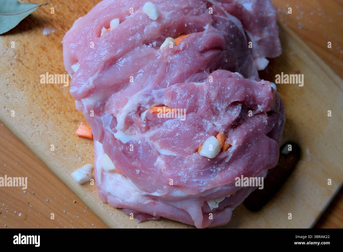 Frisch geschnittenes Schweinefleisch auf einem Holzbrett, bereit für die kulinarische Zubereitung. Stockfoto