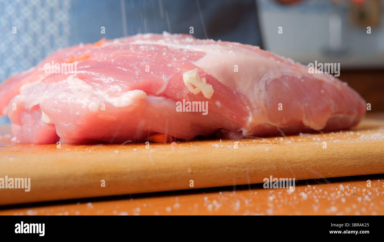 Ein rohes Schweinefleisch liegt auf einem Holzbrett, bereit zum Würzen und Kochen. Stockfoto