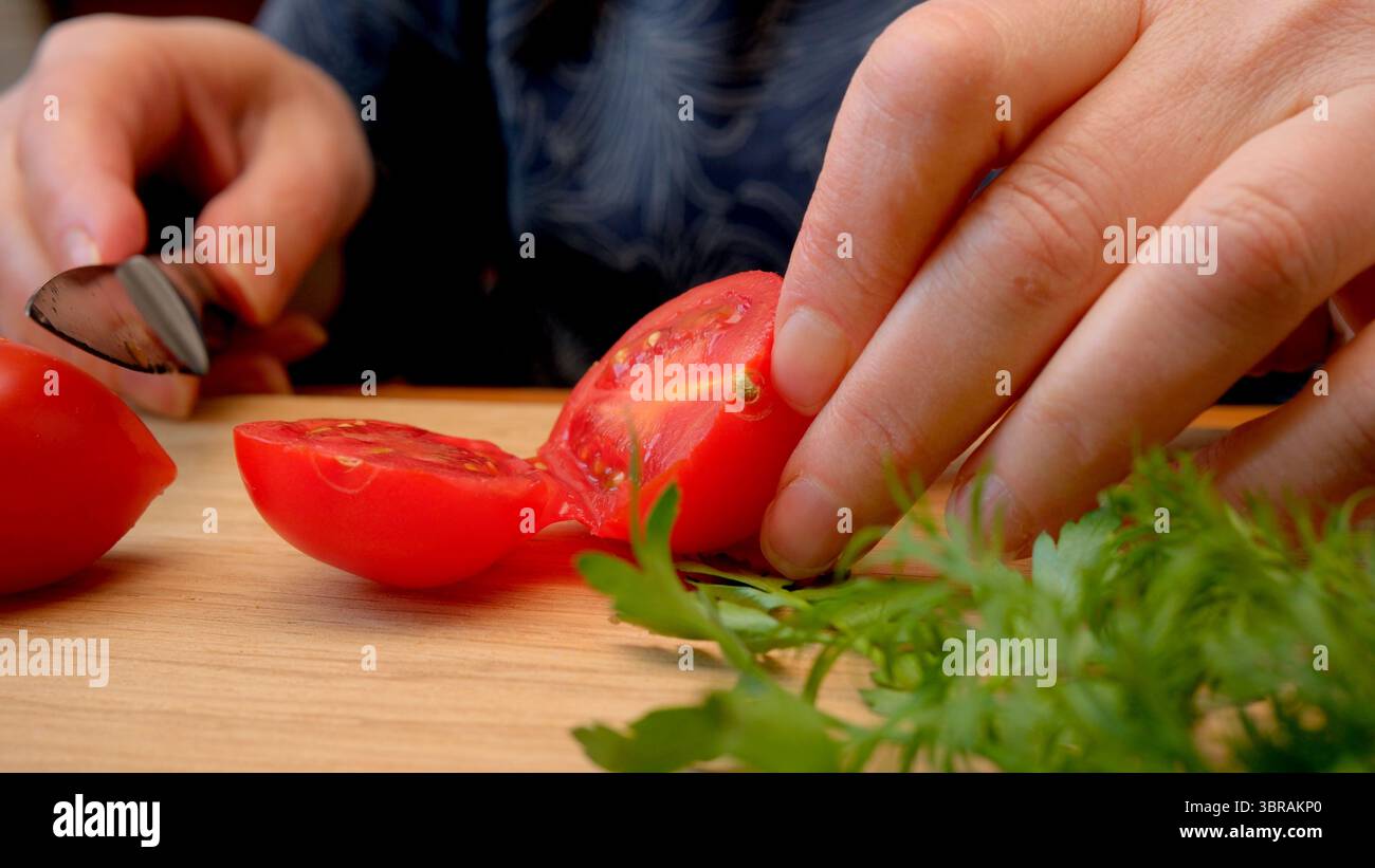 Erfahrene Hände bereiten reife Tomaten und Kräuter für leckere Salsa zu. Stockfoto
