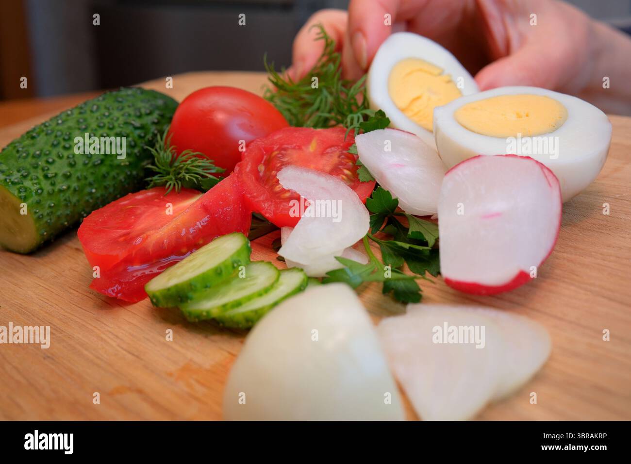 Frisches Gemüse und gekochte Eier sind kunstvoll auf einer Holzoberfläche angeordnet. Stockfoto