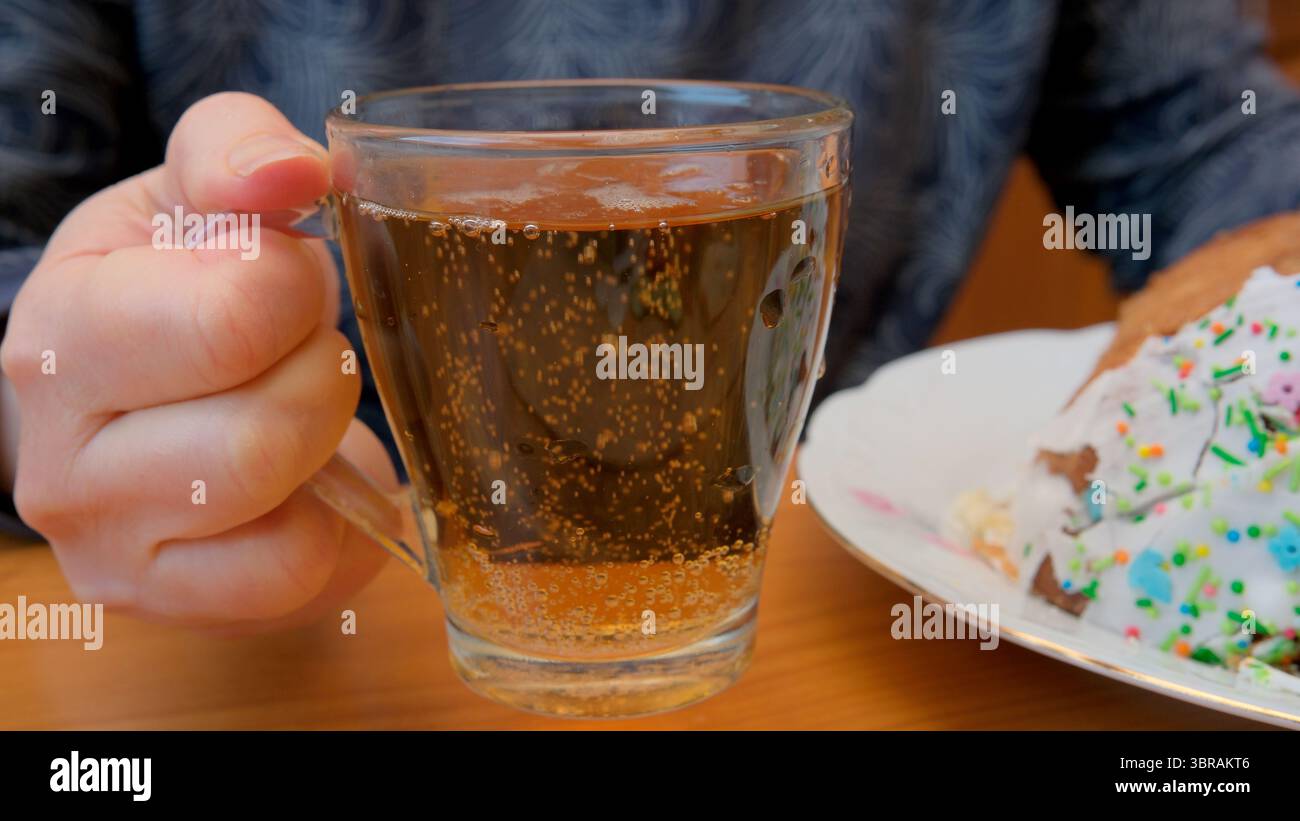 Halten Sie ein Glas prickelndes Getränk neben einem bunten Dessert. Stockfoto