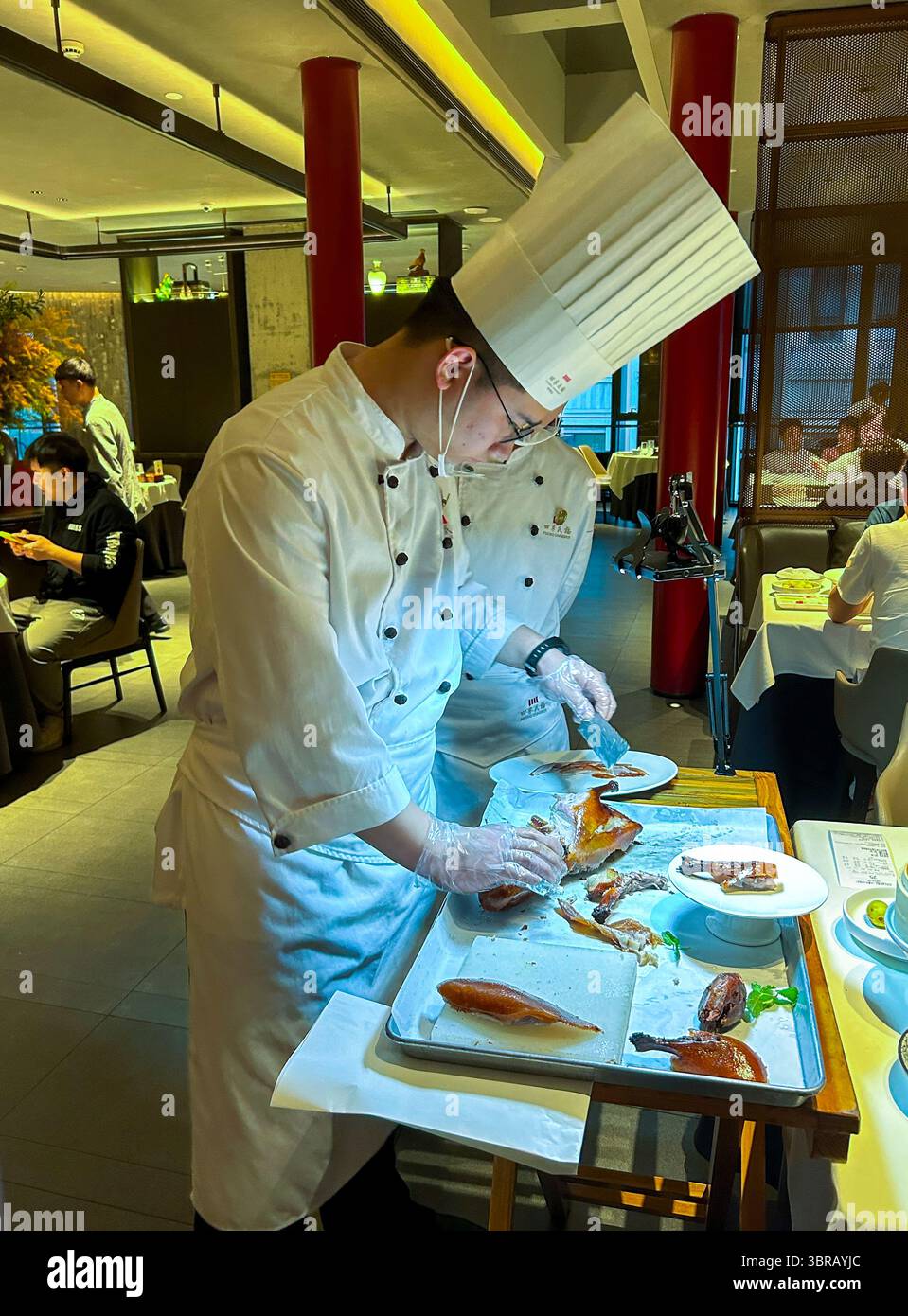 Shanghai, China, Porträt, chinesischer Küchenchef, in Uniform, Entenschnitzerei am Tisch im Speisesaal, chinesisches Restaurant, 'Peking Chamber' Stockfoto