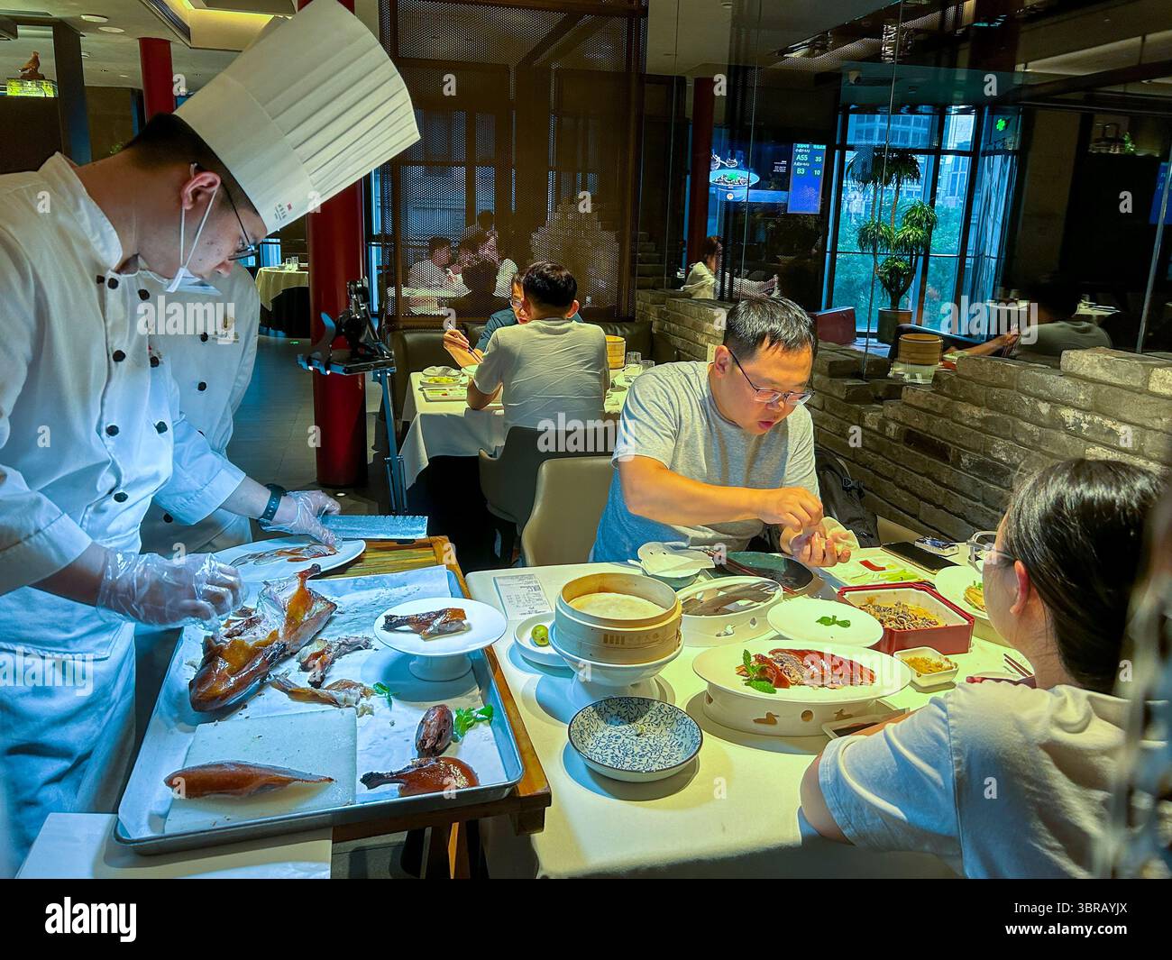 Shanghai, China, chinesischer Küchenchef, in Uniform, Ente am Tisch im Speisesaal schnitzen, chinesisches Restaurant, 'Peking Kammer » junge Leute Abendessen Stockfoto