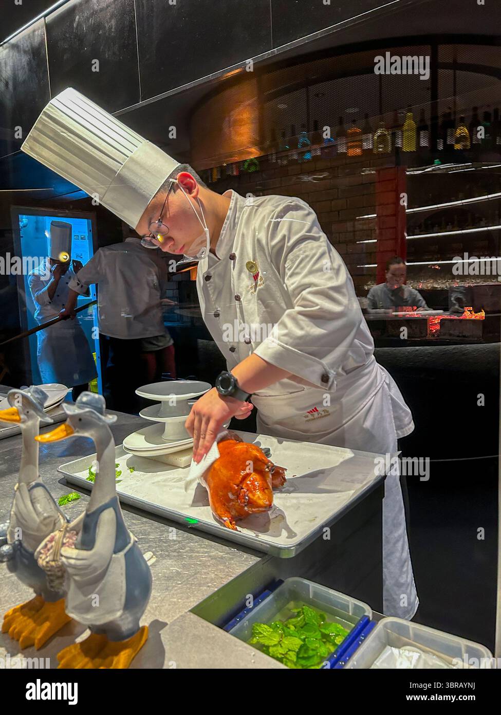 Shanghai, China, Porträt, chinesischer Küchenchef, in Uniform, Entenschnitzerei am Tisch im Speisesaal, chinesisches Restaurant, 'Peking Chamber' Stockfoto