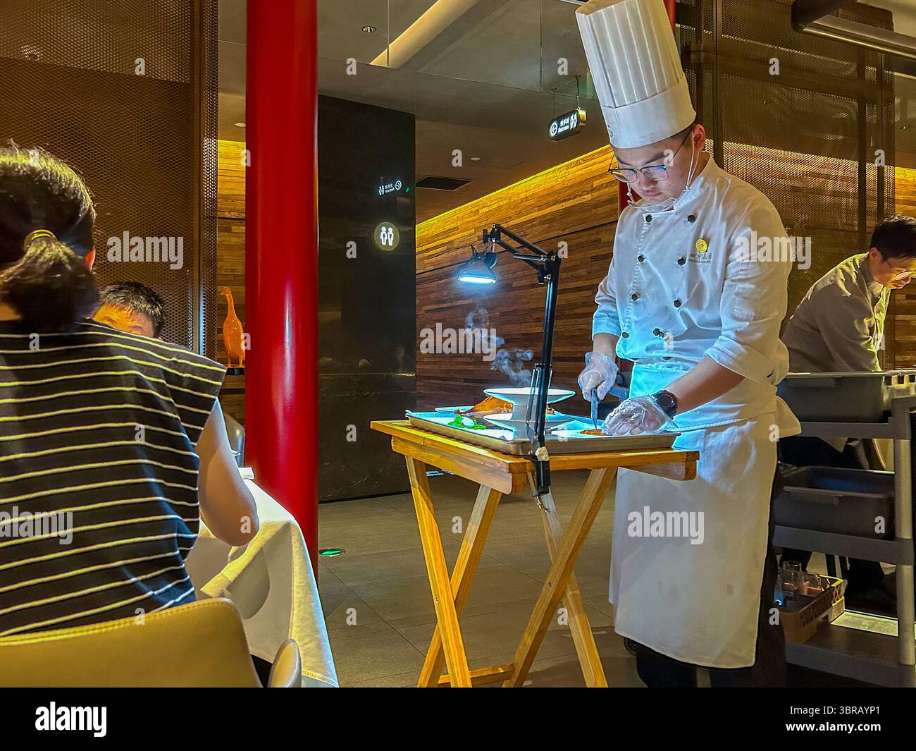 Shanghai, China, Porträt, chinesischer Küchenchef, in Uniform, Entenschnitzerei am Tisch im Speisesaal, chinesisches Restaurant, 'Peking Chamber' Stockfoto