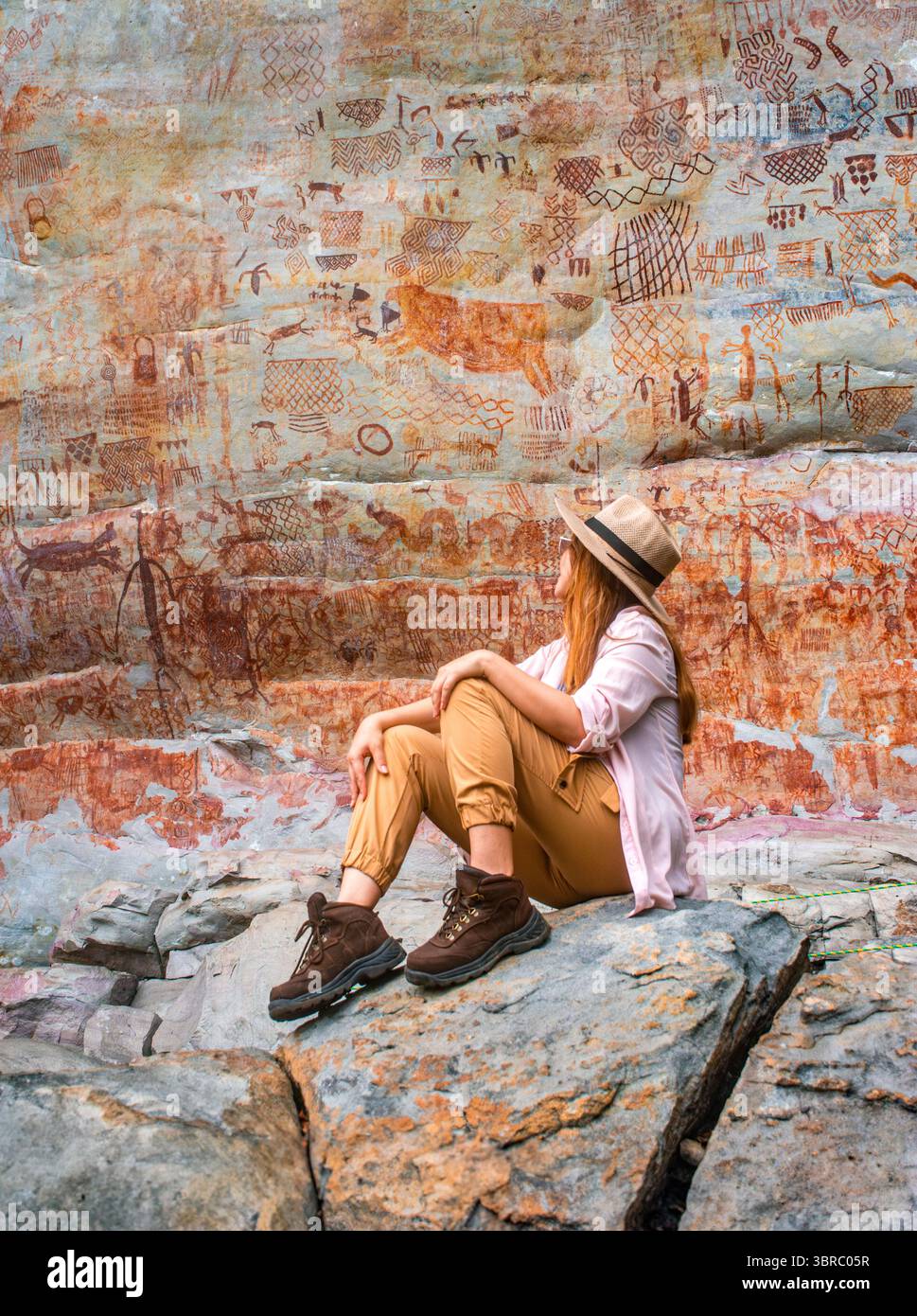 Eine Frau bewundert die antike Felskunst in Guaviare, Kolumbien, umgeben von einer atemberaubenden Naturkulisse, perfekt für abenteuerliche Urlaube. Stockfoto