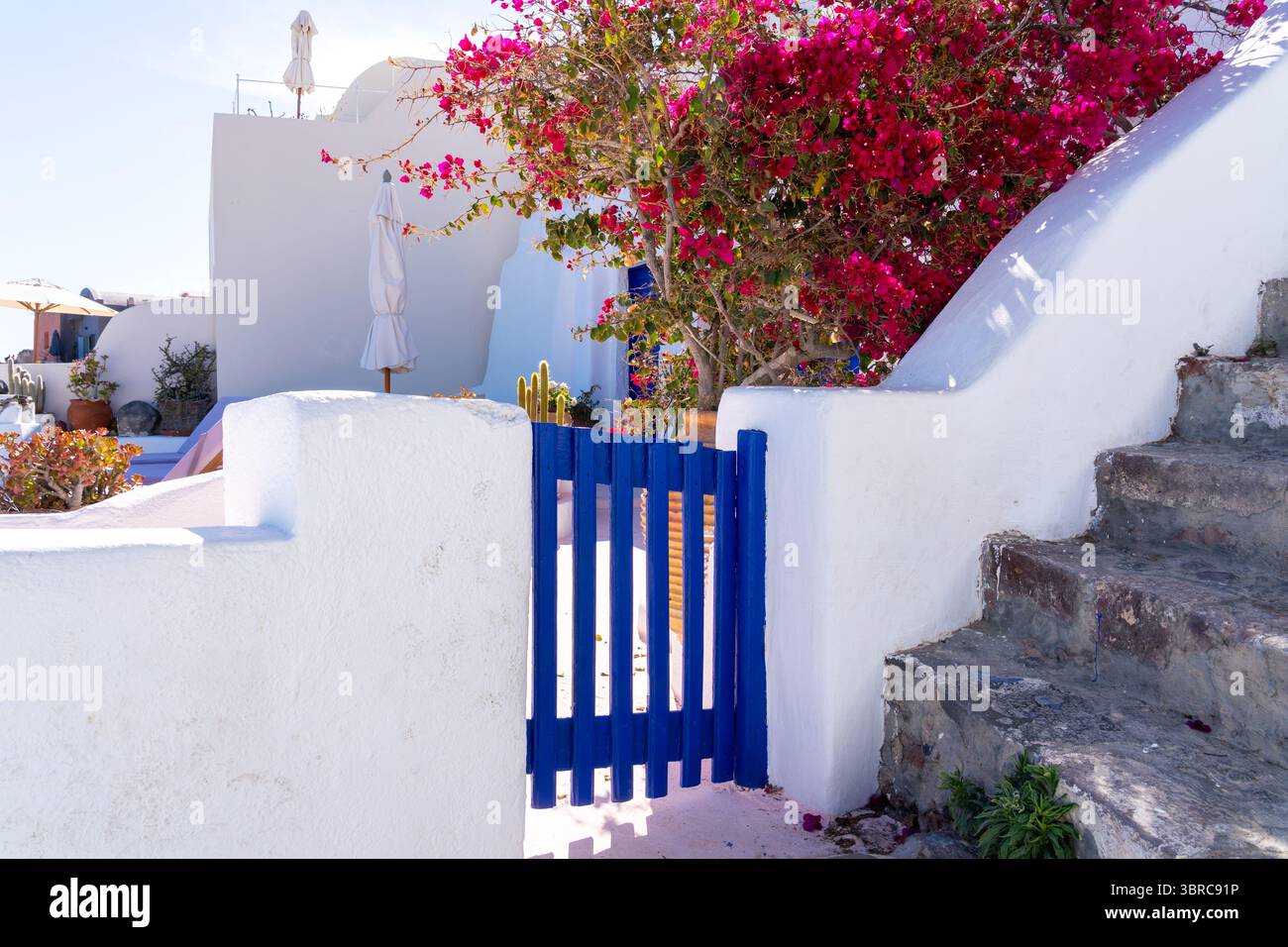 Das weiße Gebäude mit blauem Tor, Tür und Geländer in Oia, Insel Santorin, Griechenland. Stockfoto