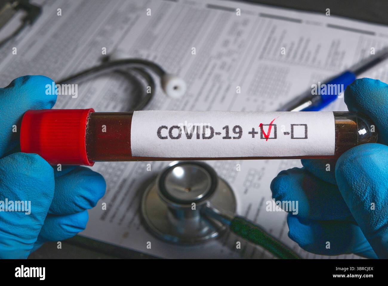 Hände mit Handschuhen, die ein Reagenzglas mit einer Blutprobe halten, die positiv auf covid-19 getestet wurde Stockfoto