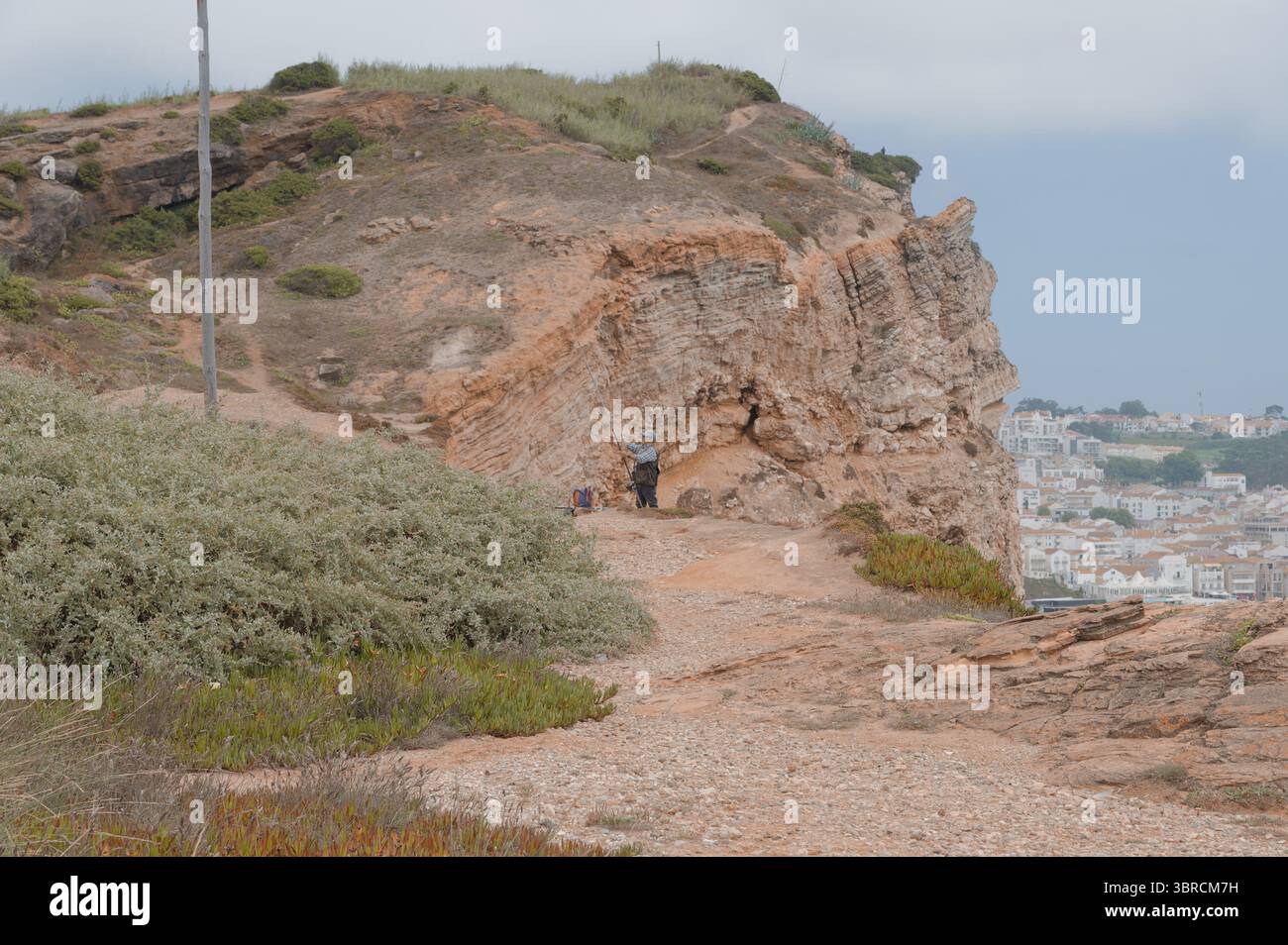 Fisherman bereitet seine Rute auf den zerklüfteten Klippen von Nazaré vor, die die Stadt überblicken Stockfoto