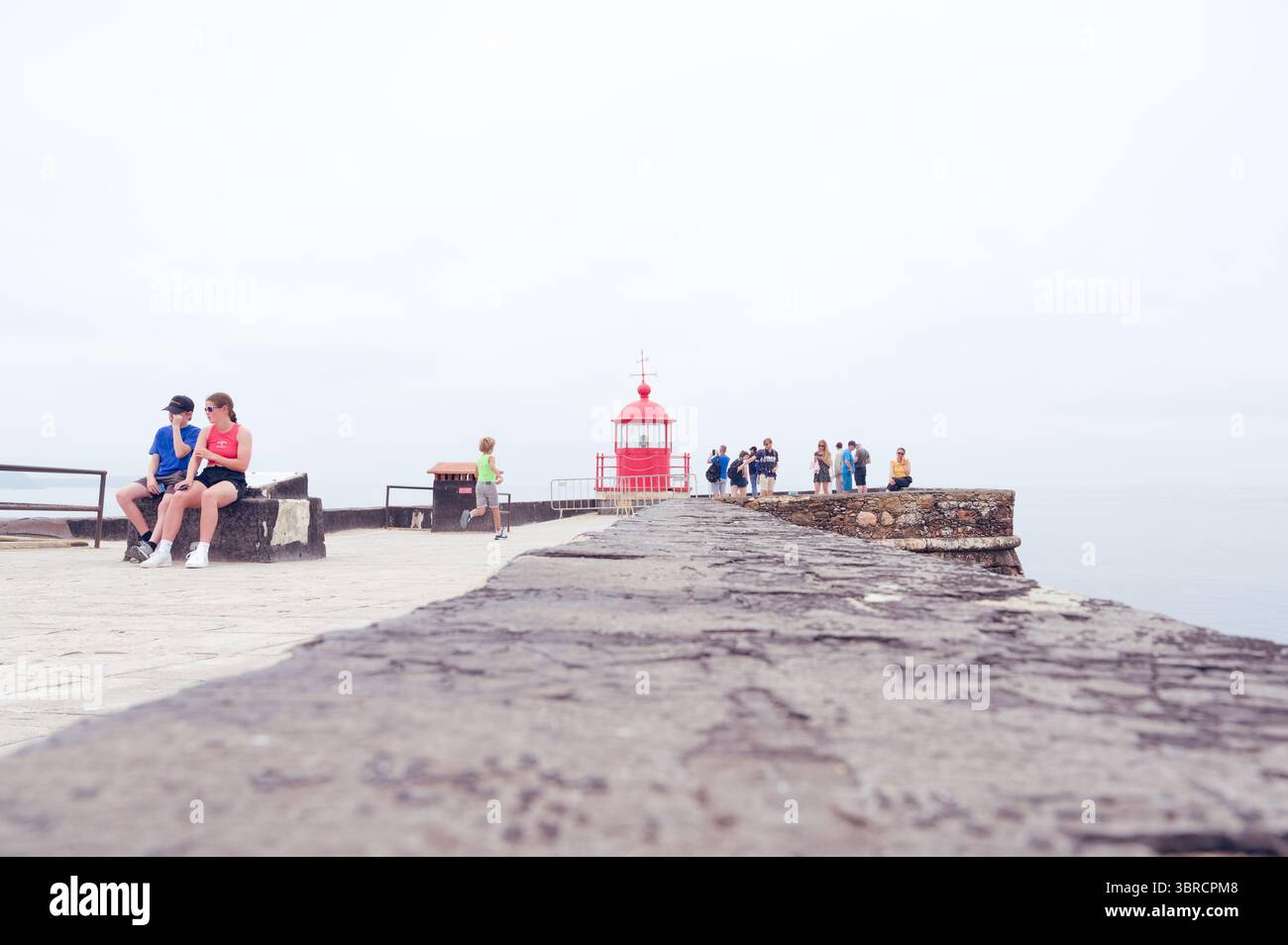 Besucher entspannen sich und erkunden die Nähe des berühmten roten Leuchtturms auf der Forte de São Miguel Arcanjo Stockfoto