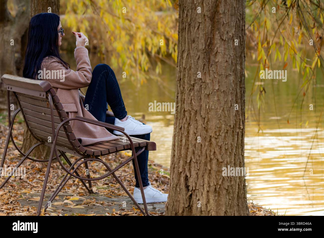 Eine junge Frau, die ihre Hand auf einer Bank im Park sieht Stockfoto