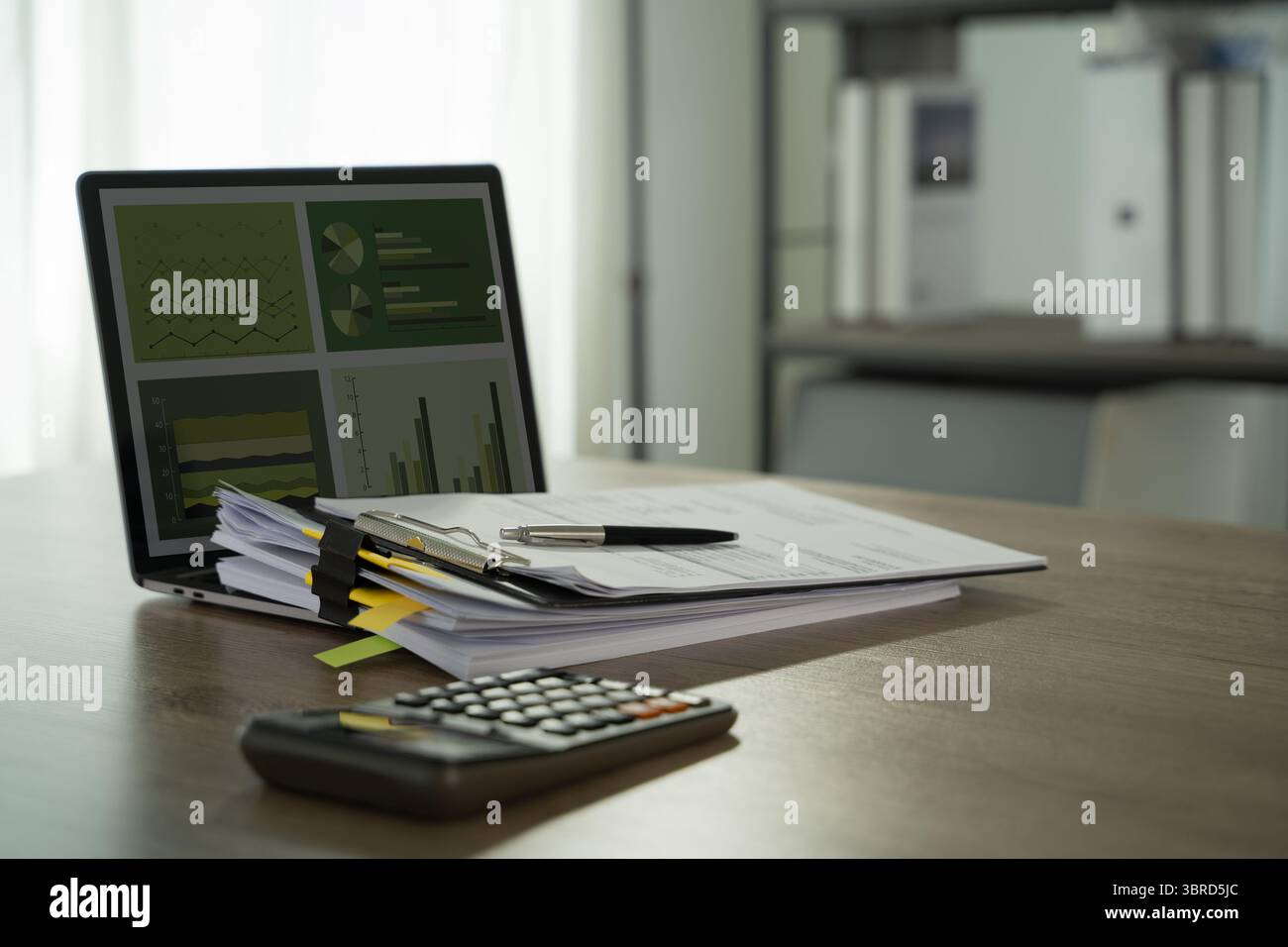 Ein umweltfreundlicher, aufgeräumter Büroarbeitsplatz mit Dokumenten, Stift, Taschenrechner und Laptop, der Diagramme und Diagramme anzeigt und finanzielle Vorschläge vorschlägt Stockfoto