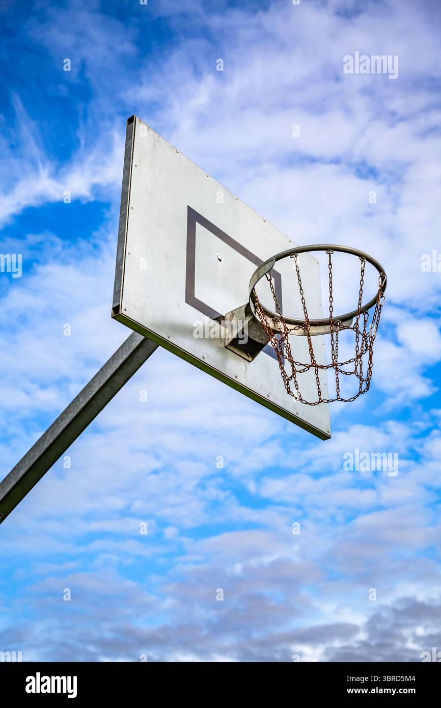 Sonniger Tag auf dem Platz im Freien mit einem Basketballkorb vor blauem Himmel und Kopierraum Stockfoto