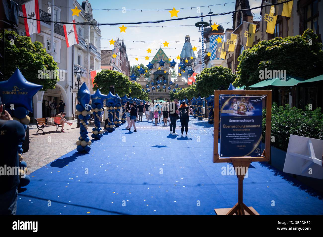 Rust, Deutschland, Europa Europa-Park feiert 50-jähriges Jubiläum mit blau-goldenem Festaufbau, Sommernachtsparty, Überraschungsmoment, festlich geschmückte Straße mit Sternen und Ballons, Familienevent, Freizeitpark, Jubiläum, Tourismus, Unterhaltung, Eventkultur *** Rust, Deutschland, Europa Europa Park feiert sein 50-jähriges Bestehen mit blauen und goldenen Festdekorationen, Sommernachtparty, Überraschungsmoment, festlich geschmückte Straße mit Sternen und Ballons, Familienevent, Themenpark, Jubiläum, Tourismus, Unterhaltung, Veranstaltungskultur Copyright: xFinleyxMoerchx Stockfoto
