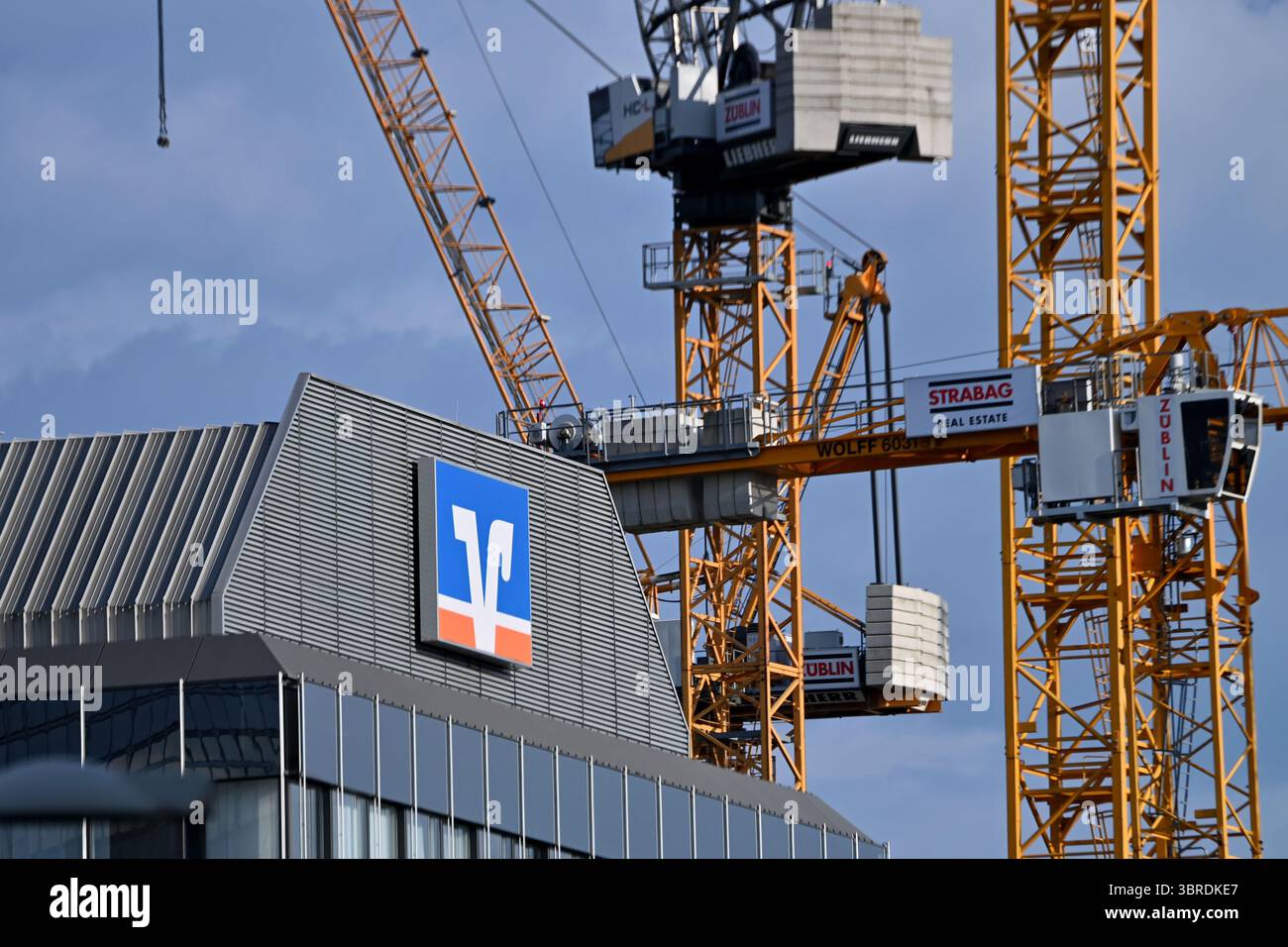 München, Deutschland. Juli 2025. Betrefffoto: Volksbank Raiffeisenbank EG, Logo, Banklogo, Firmenlogo, Firmenlogo. Dahinter befinden sich Baukräne, Baustelle? Quelle: dpa/Alamy Live News Stockfoto
