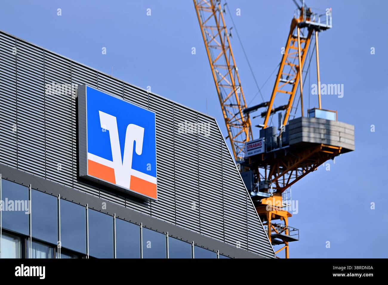 München, Deutschland. Juli 2025. Betrefffoto: Volksbank Raiffeisenbank EG, Logo, Banklogo, Firmenlogo, Firmenlogo. Dahinter befinden sich Baukräne, Baustelle? Quelle: dpa/Alamy Live News Stockfoto