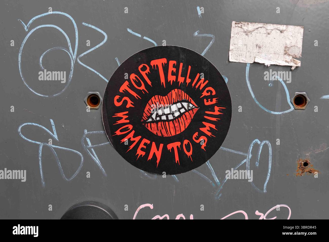 Hör auf, Frauen zu sagen, sie sollen lächeln. Feministischer Aufkleber auf einem öffentlichen Abfalleimer in Tampere, Finnland. Stockfoto