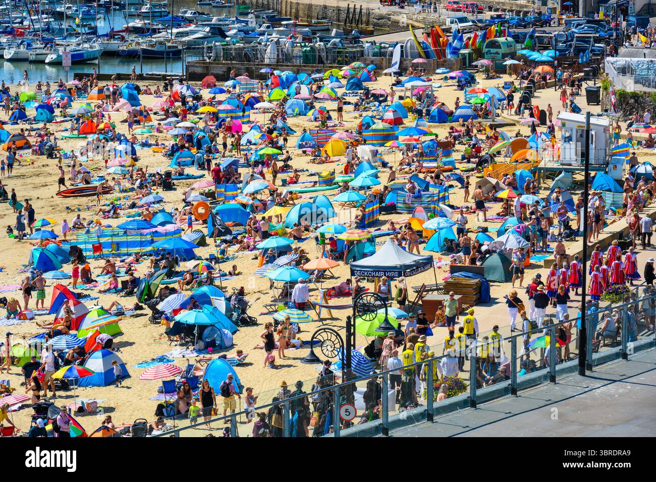 Lyme Regis, Dorset, Großbritannien. Juli 2025. Wetter in Großbritannien. Die Menschenmassen strömen zum überfüllten Strand im malerischen Badeort Lyme Regis, um sich in der heißen Sonne zu sonnen und den Lyme Morris Day zu genießen. Der Strand wurde mit Leuten gesäumt, die die Sonne aufsaugen und die Morris-Tanzvorführungen entlang der Marine Parade genossen. Die Temperaturen werden heute wieder auf 30 °C steigen. Das Met Office gibt einen gelben Alarm für Hitze in ganz Großbritannien aus, während die Hitzewelle im Juli bis ins Wochenende andauert. Quelle: Celia McMahon/Alamy Live News Stockfoto