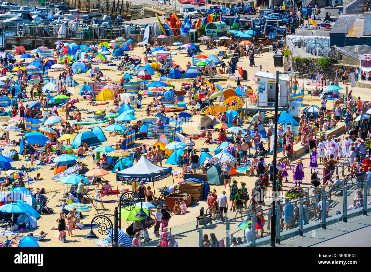 Lyme Regis, Dorset, Großbritannien. Juli 2025. Wetter in Großbritannien. Die Menschenmassen strömen zum überfüllten Strand im malerischen Badeort Lyme Regis, um sich in der heißen Sonne zu sonnen und den Lyme Morris Day zu genießen. Der Strand wurde mit Leuten gesäumt, die die Sonne aufsaugen und die Morris-Tanzvorführungen entlang der Marine Parade genossen. Die Temperaturen werden heute wieder auf 30 °C steigen. Das Met Office gibt einen gelben Alarm für Hitze in ganz Großbritannien aus, während die Hitzewelle im Juli bis ins Wochenende andauert. Quelle: Celia McMahon/Alamy Live News Stockfoto