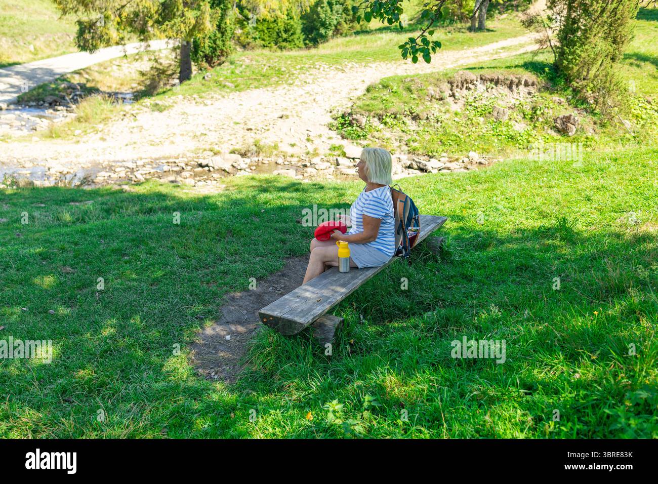 Seniorin ruht auf einer Bank während der Wanderung in der Natur Stockfoto