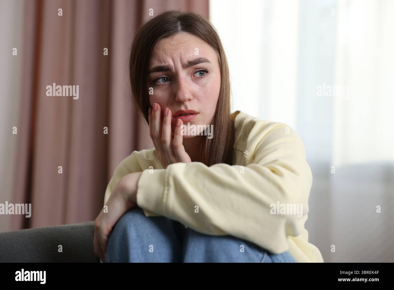 Verängstigte Frau, die zu Hause an Paranoia leidet Stockfoto